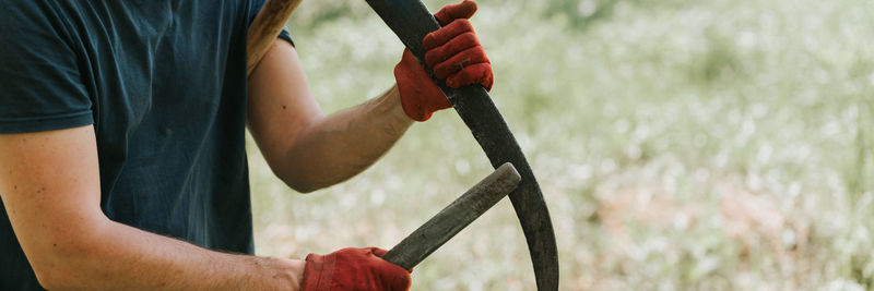 Mowing grass with scythe on farm. farmer man sharpening scythe with grass or whetstone for mowing