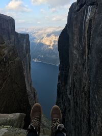 Low section of man on cliff against lake and mountain
