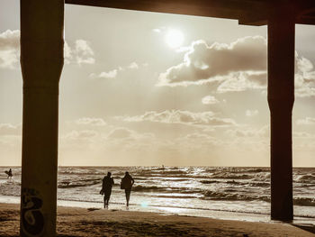 People walking at beach against sky