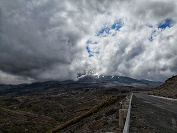 Scenic view of road by mountains against sky