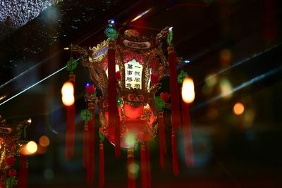 Low angle view of illuminated red lantern hanging by glass