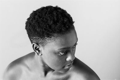 Close-up portrait of shirtless young woman over white background