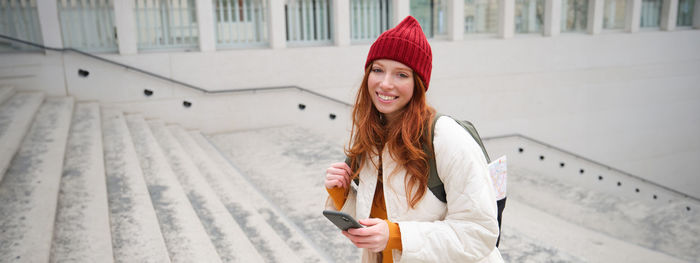 Young woman standing against building