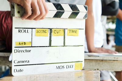 Midsection of man holding film slate while standing outdoors