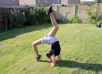 Teenage girl doing acrobatic exercises on a green lawn, sport, generation z,