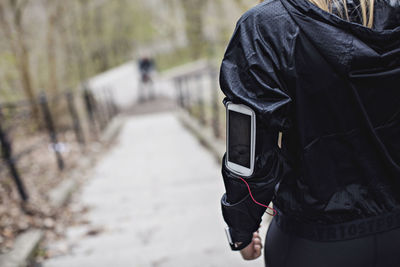 Midsection of fit woman with smart phone on arm band