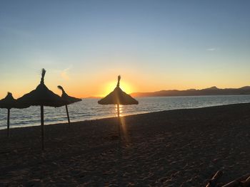 Silhouette beach by sea against sky during sunset