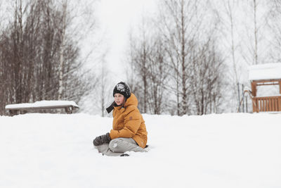 Girl in plays in backyard and enjoys sunny day in winter, she stands on snowdrift 