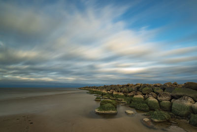 View of calm beach against cloudy sky