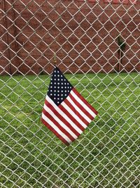 Close-up of american flag on chainlink fence at field