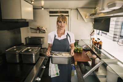 Portrait of confident chef holding container with food in truck