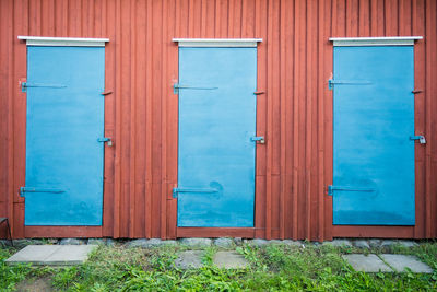 Three closed blue doors in red building