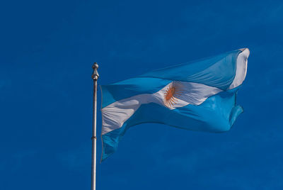 Low angle view of flag against blue sky