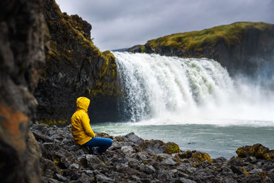 Rear view of man looking at waterfall