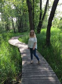 Portrait of woman standing on boardwalk in forest