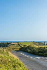 Road by sea against clear sky
