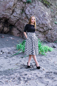 Full length portrait of woman standing on rock against tree