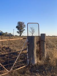 Fence on field against clear blue sky