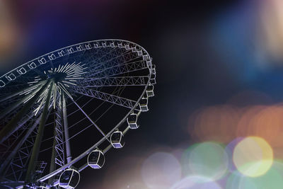 Low angle view of illuminated ferris wheel against sky at night