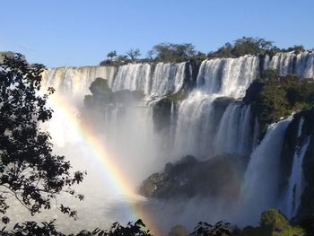 Scenic view of waterfall against rainbow in sky