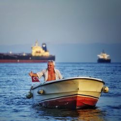 Portrait of man in boat on sea against clear sky