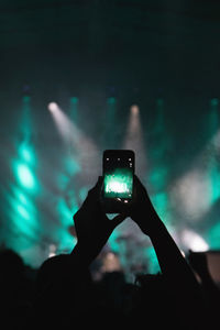 Silhouette hands photographing music concert with smart phone