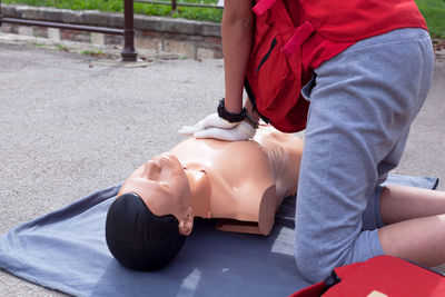 Midsection of paramedic performing cpr on mannequin