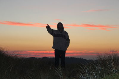 Man standing on field against sky during sunset