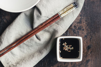 Soy sauce and sesame in a vessel and bamboo chopsticks