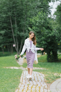 A pretty young woman holds a bouquet of pink garden spirea flowers in her hands. walking in nature