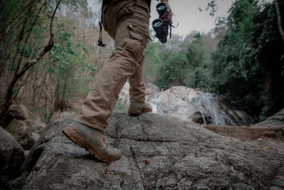 Low section of man standing on rock in forest