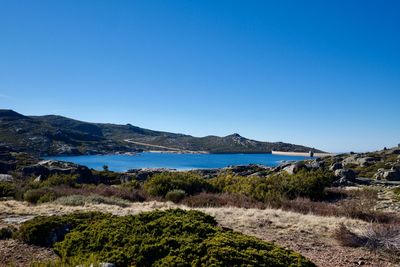 Scenic view of sea and mountains against clear blue sky