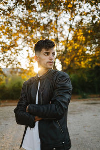 Young man standing against tree