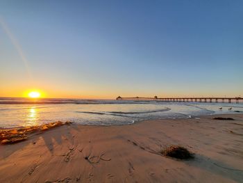 Scenic view of beach against clear sky during sunset