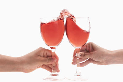 Cropped hand of woman holding wineglass against white background