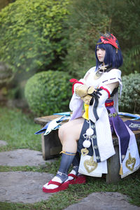 Young woman using mobile phone while sitting on field