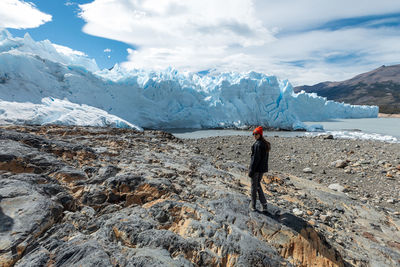 Rear view of person standing on snowcapped mountain