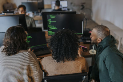 Multiracial female and male hackers coding on computer while working at creative workplace