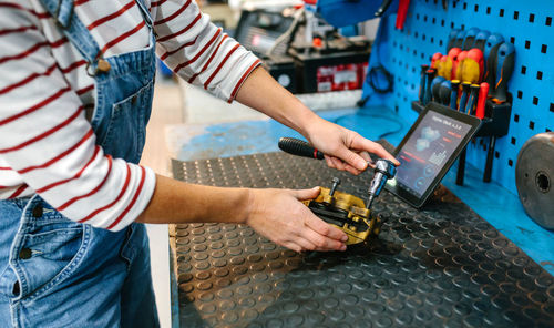 Mechanic woman repairing caliper brake system over workbench