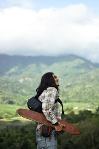 Rear view of man standing on mountain against sky