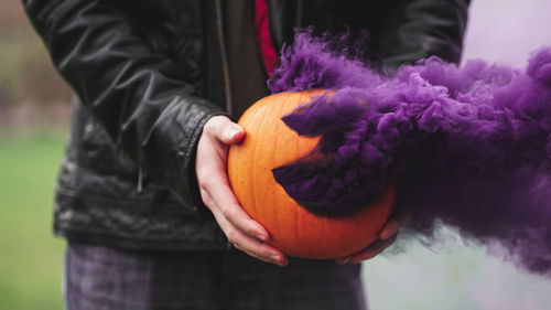 Midsection of man holding pumpkin while standing outdoors