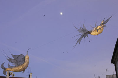 Low angle view of birds flying against clear sky