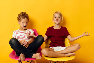 Portrait of happy family sitting on sofa against yellow background