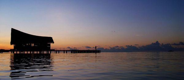 Pier in sea at sunset