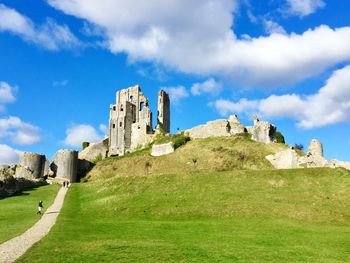 Low angle view of old ruin on hill against cloudy sky during sunny day