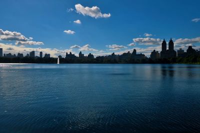 View of city at waterfront against cloudy sky