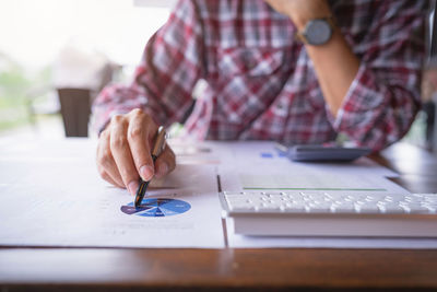 Midsection of man using mobile phone on table