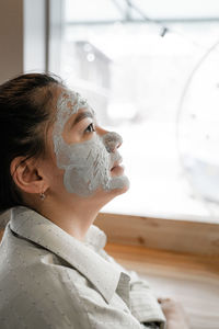 Close-up of woman with facial mask looking away