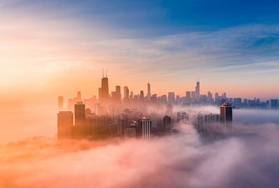 Buildings in city against sky during sunset