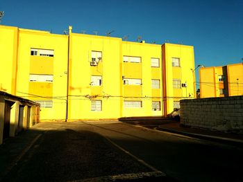 Yellow road by building against sky in city